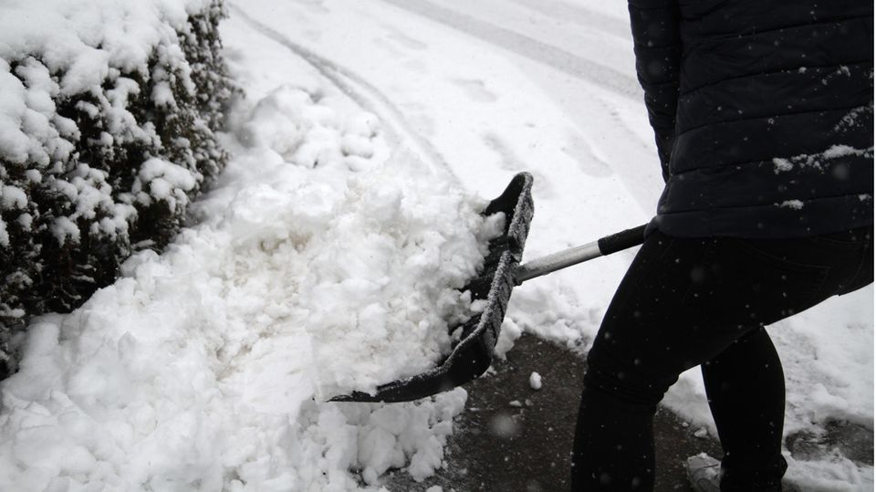Morgenlage: Person beim Schneeschippen