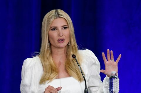 Ivanka Trump steht vor einem blauen Hintergrund und gestikuliert