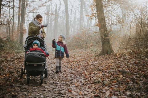 Winterfußsack: Mutter streichelt ihr Kleinkind, das im Buggy in einem Winterfußsack liegt