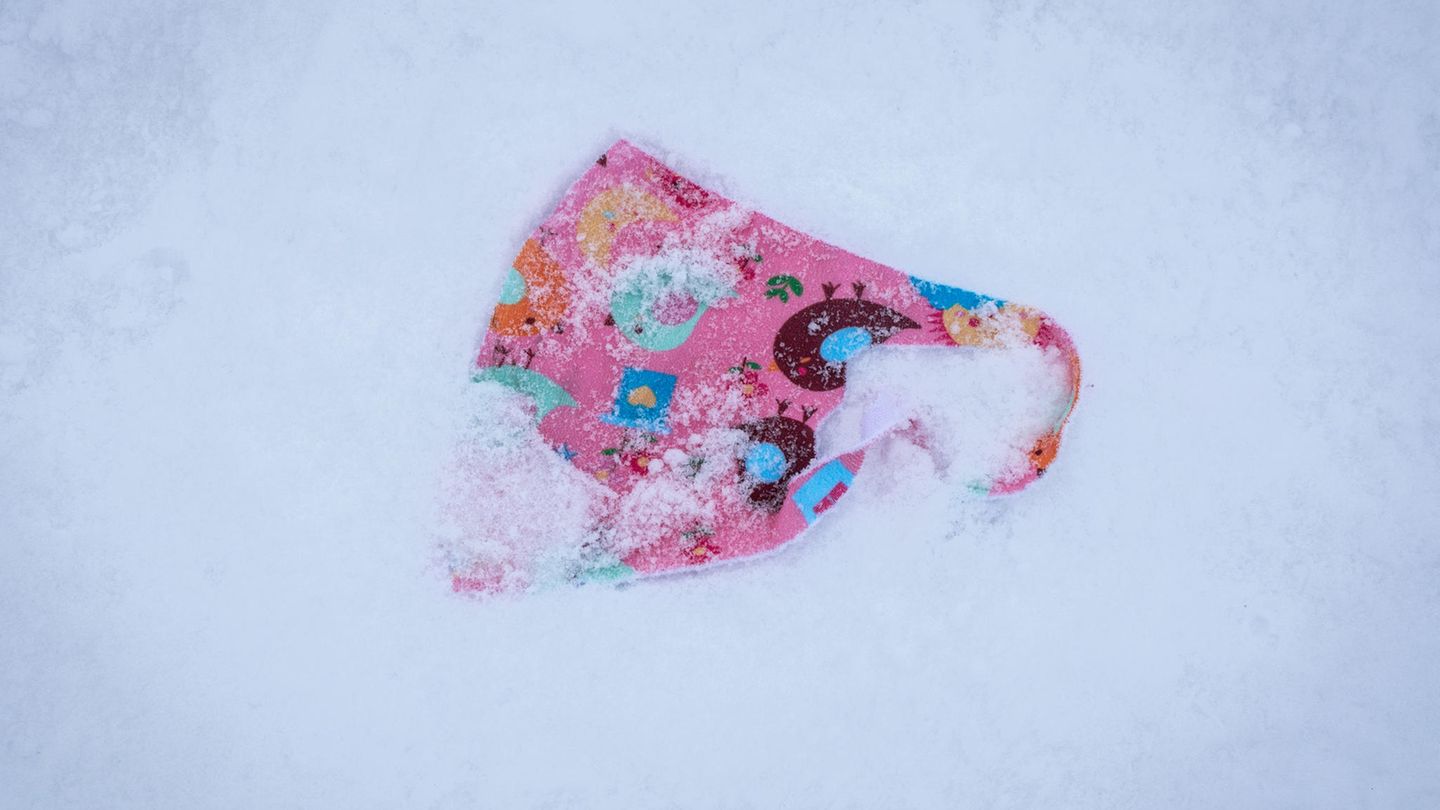Ein verlorener, bunt gemusterter Mund-Nasen-Schutz für Kinder liegt im Schnee auf dem Gipfelplateau des Großen Feldbergs