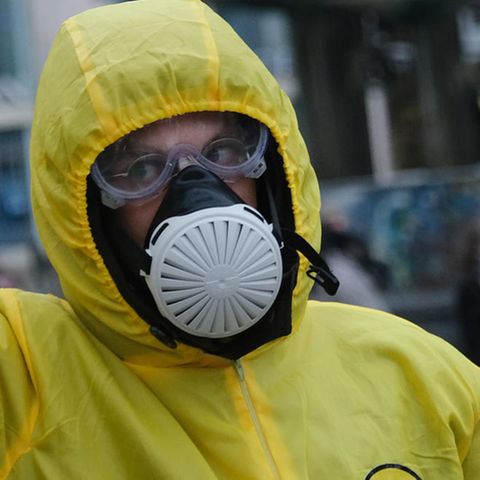 Bei einer "Querdenken"-Demo in Berlin trägt ein Mann einen gelben Overall mit Kapuze sowie Schutzbrille und Atemmaske