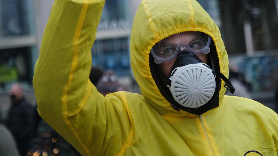 Bei einer "Querdenken"-Demo in Berlin trägt ein Mann einen gelben Overall mit Kapuze sowie Schutzbrille und Atemmaske