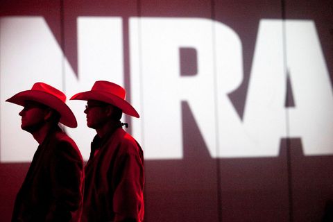 Zwei Männer mit Cowboyhüten stehen vor dem Logo der NRA