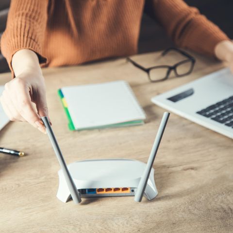 Eine Frau richtet die Antennen ihres Routers aus.
