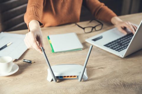 Eine Frau richtet die Antennen ihres Routers aus.