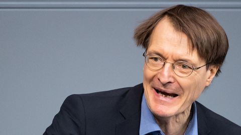 SPD-Gesundheitsexperte Karl Lauterbach steht in blauem Anzug am Rednerpult im Bundestag und gestikuliert mit der rechten Hand