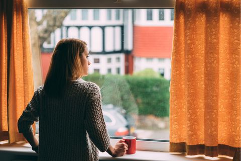 Eine junge Frau guckt aus dem Fenster