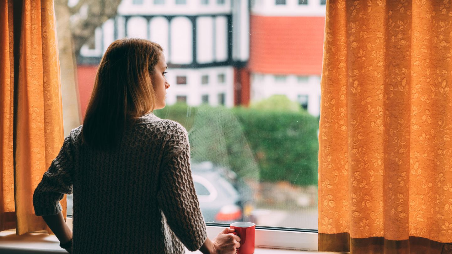 Eine junge Frau guckt aus dem Fenster
