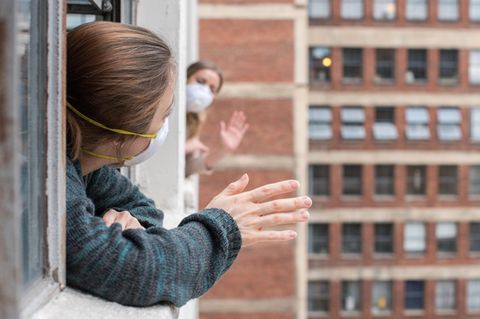 Nachbarn winken sich aus dem Fenster zu