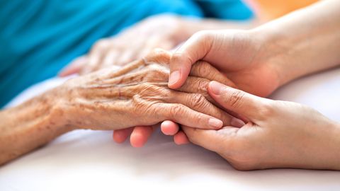 Altenpflege: Eine junge Frau hält die Hand einer älteren Frau