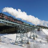 An einem Wintertag mit strahlender Sonne und blauem Himmel: Der lange Zug wird von zwei Lokomotiven gezogen.