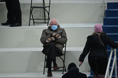 Bernie Sanders trägt Fäustlinge und sitzt auf einem Klappstuhl