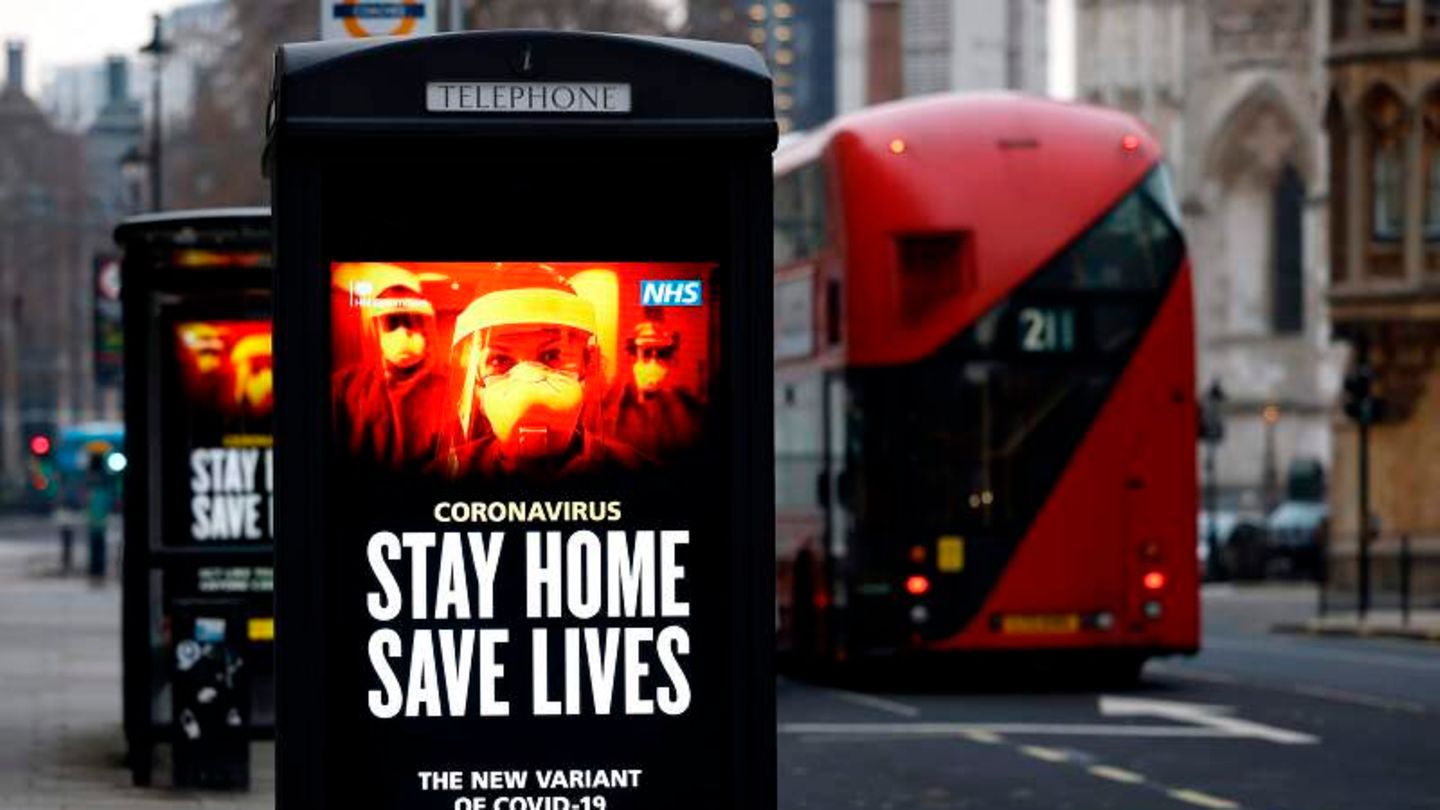 Ein Plakat mit Maßnahmen gegen das Coronavirus in London, daneben ein roter Bus