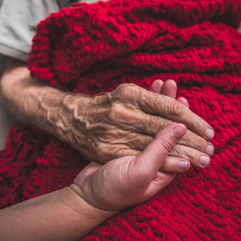 Pflege: Eine Frau hält die Hand eines älteren Mannes