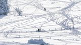 Im Gegenlicht bei Sonnenschein: Menschen genießen während eines Spaziergangs die verschneite Landschaft auf dem Schauinsland in Baden-Württemberg.