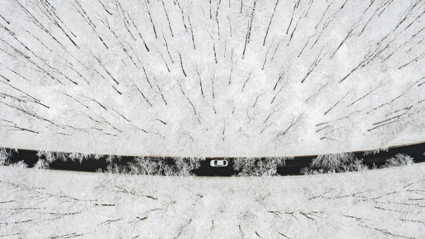 Bei Winterberg in Nordrhein-Westfalen: Ein Auto fährt über eine Straße durch einen verschneiten Wald.