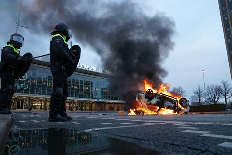 Flammen schlagen aus einem Auto, das vor dem Bahnhof in Eindhoven auf dem Kopf liegt