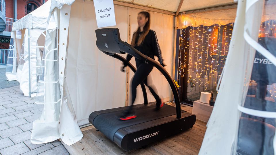 Fitnessstudio Zelt Hamburg Frau Laufband In einem weißen Party-Pavillion trainiert eine junge Frau ganz in Schwarz auf einem Laufband