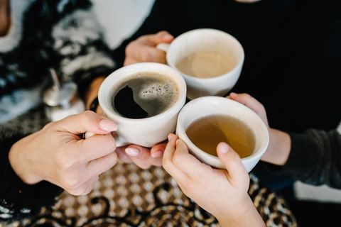 Hände halten Tassen mit Kaffee und Tee