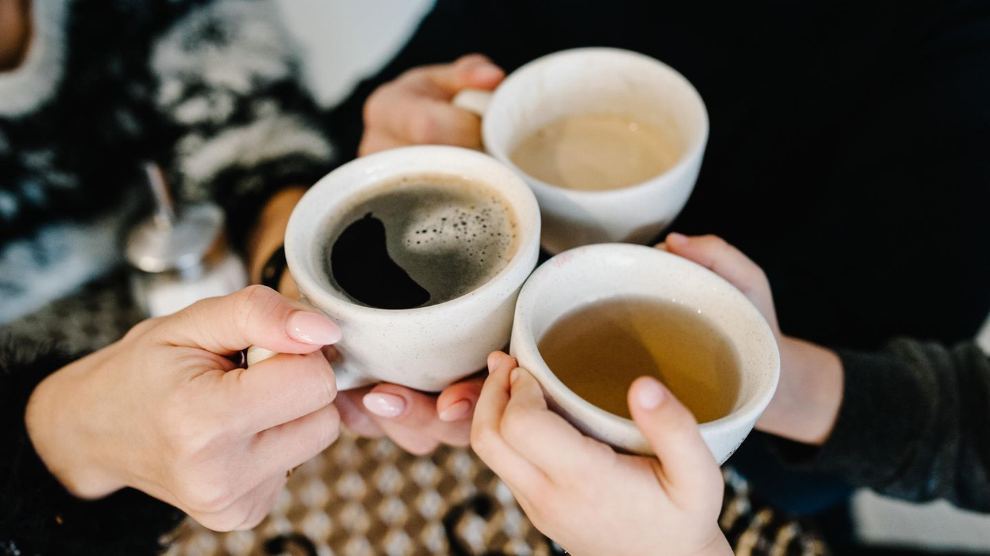 Hände halten Tassen mit Kaffee und Tee