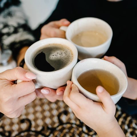 Hände halten Tassen mit Kaffee und Tee