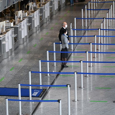 Mitarbeiter einer Fluggesellschaft stehen vor leeren Abflugschaltern am Frankfurt Airport