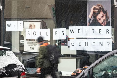 In einem Schaufenster eines Friseursalons steht  "Wie soll es weitergehen?" auf Schildern