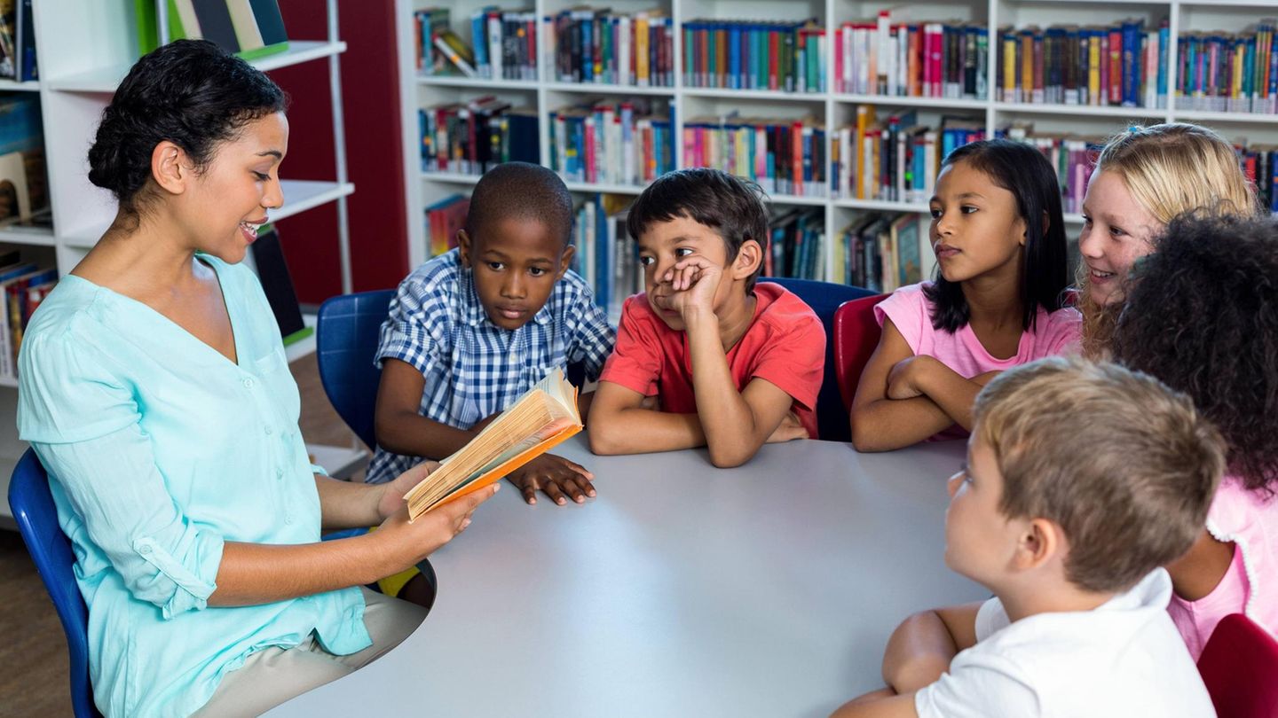 Eine Lehrerin liest einer Gruppe Kindern ein Buch vor