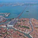 Venedig – Italien  Diese Luftaufnahme zeigt Venedig und den Hauptbahnhof Santa Lucia. Er ist ein Kopfbahnhof und der einzige Bahnhof auf der Insel von Venedig. Seinen Namen hat er von der Santa-Lucia-Kirche, die ursprünglich an diesem Ort stand und für den Bau des Bahnhofs 1861 abgerissen wurde. Über den Ponte della Libertà ist der Bahnhof mit dem Knotenbahnhof Venezia Mestre auf dem Festland verbunden.