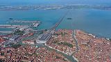 Venedig – Italien  Diese Luftaufnahme zeigt Venedig und den Hauptbahnhof Santa Lucia. Er ist ein Kopfbahnhof und der einzige Bahnhof auf der Insel von Venedig. Seinen Namen hat er von der Santa-Lucia-Kirche, die ursprünglich an diesem Ort stand und für den Bau des Bahnhofs 1861 abgerissen wurde. Über den Ponte della Libertà ist der Bahnhof mit dem Knotenbahnhof Venezia Mestre auf dem Festland verbunden.