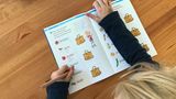 Schreiben und Lesenlernen in der ersten Klasse. Der Sechsjährige braucht noch viel Motivation. Er kann vieles schon allein, möchte aber, dass jemand bei ihm sitzt.