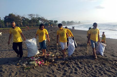 Am Saba Beach auf Bali: Teilnehmer einer Müllsammelaktionen von Trash Hero sammeln an einem Strand mit langen Zangen Unrat auf. 