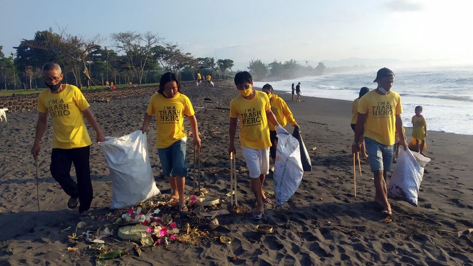 Am Saba Beach auf Bali: Teilnehmer einer Müllsammelaktionen von Trash Hero sammeln an einem Strand mit langen Zangen Unrat auf. 