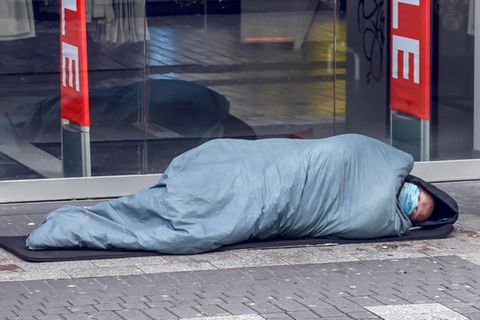 Ein Obdachloser vor einem Modegeschäft in Köln