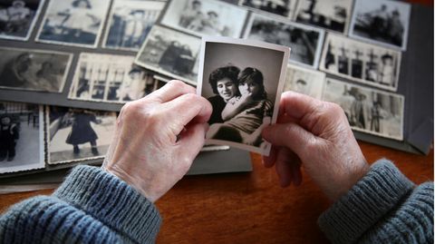 Altenpflege: Eine ältere Frau sieht sich alte Fotos an