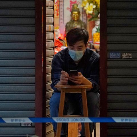 Ein Mann vertreibt sich die Zeit mit seinem Smartphone, während er auf sein Corona-Testergebnis wartet. Bewohner im gesperrten Bereich des Honkonger Bezirks Sham Shui Po sind verpflichtet, über Nacht zu Hause zu bleiben, bis sie einen negativen Corona-Test vorweisen können.