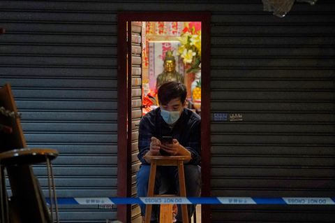 Ein Mann vertreibt sich die Zeit mit seinem Smartphone, während er auf sein Corona-Testergebnis wartet. Bewohner im gesperrten Bereich des Honkonger Bezirks Sham Shui Po sind verpflichtet, über Nacht zu Hause zu bleiben, bis sie einen negativen Corona-Test vorweisen können.