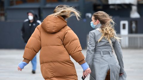 Passanten gehen in Köln über die windige Domplatte