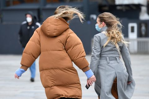 Passanten gehen in Köln über die windige Domplatte
