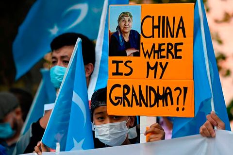 Ein junger Uiguren-Aktivist hält ein Plakat hoch: "China wo ist meine Oma?!" 