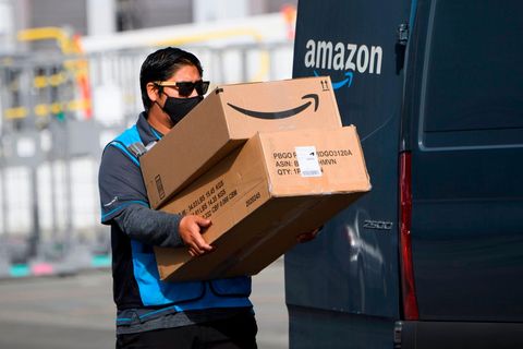 Ein Amazon-Fahrer trägt Pakete