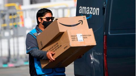 Ein Amazon-Fahrer trägt Pakete
