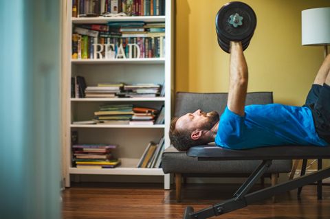 Fitnessgeräte für Zuhause: Mann liegt auf einer Hantelbank und trainiert mit Gewichten