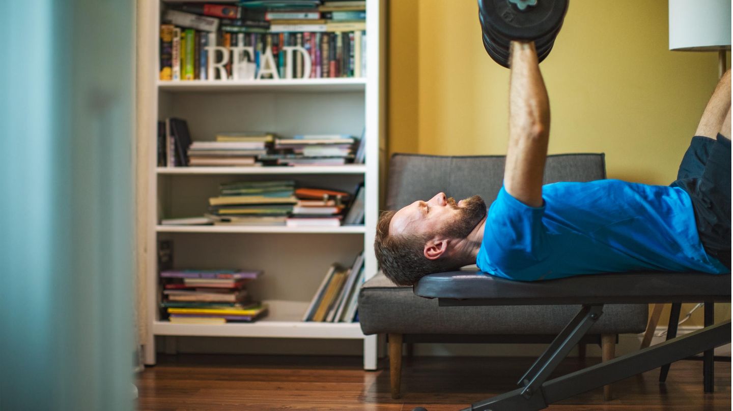 Fitnessgeräte für Zuhause: Mann liegt auf einer Hantelbank und trainiert mit Gewichten