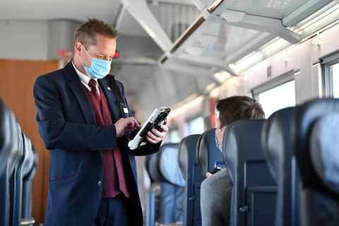 Ein Zugbegleiter der Deutschen Bahn bei der Fahrkartenkontrolle