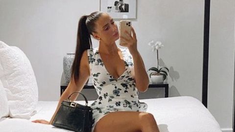 Model Isabelle Eleanore sitzt auf einem Bett und macht ein Selfie von sich
