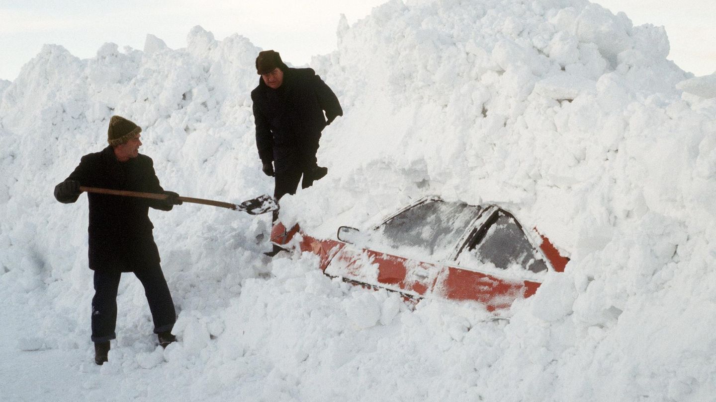 Winter 1979: Zwei Männer graben in Schleswig-Holstein mit einer Schaufel ein Auto aus den Schneemassen
