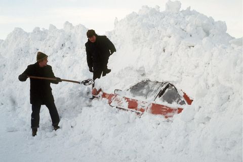 Winter 1979: Zwei Männer graben in Schleswig-Holstein mit einer Schaufel ein Auto aus den Schneemassen