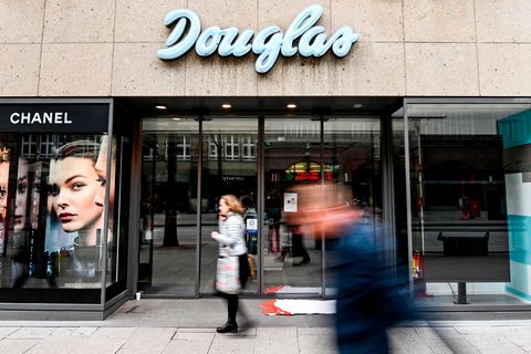 Passanten laufen vor dem geschlossenen Eingang eines Kaufhauses der Parfümerie-Filialkette Douglas in Hamburg