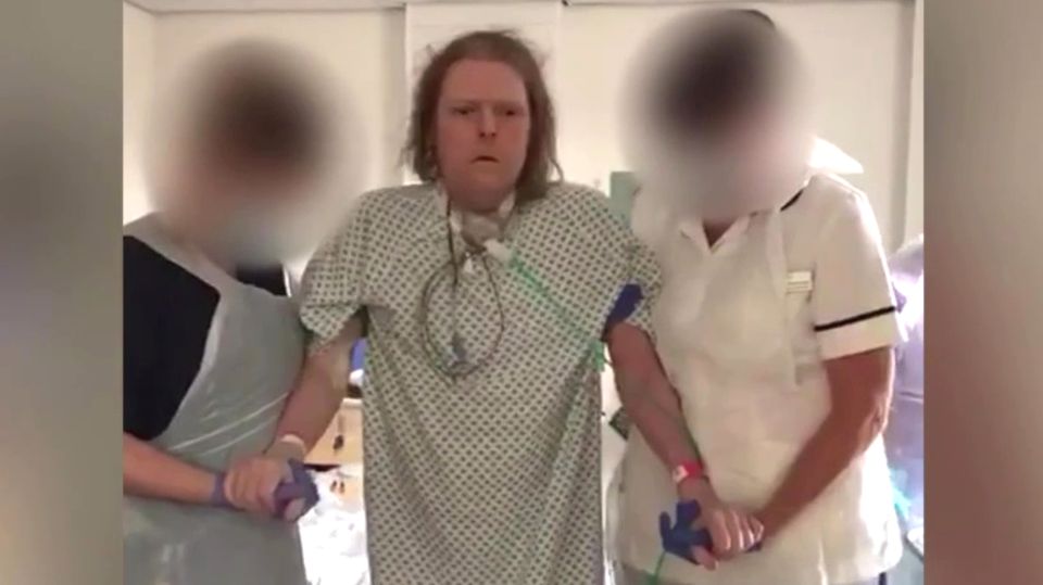 Covid-Patient kann erstmals nach zehn Monaten wieder gehen Jason Kelk wird von zwei Krankenschwestern des St James Hospital gestützt